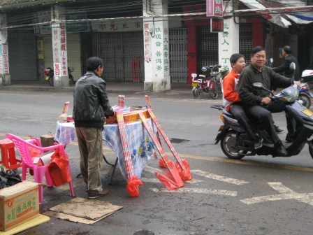 Drive-up firework sales in Haikou; the father and son on the scooter completed a purchase a second before I snapped this photo.