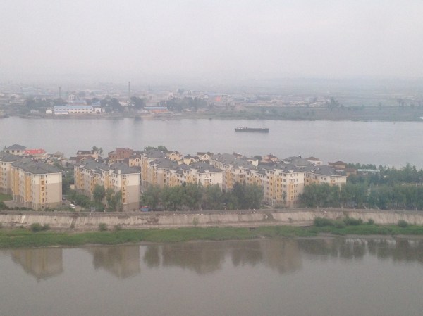 The buildings in the foreground are China; the land in the background is North Korea.