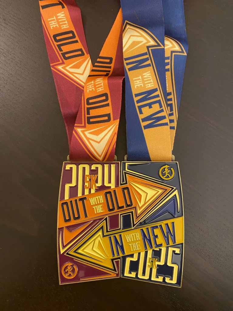 Two race medals click together to create a single square medal. One says "Out With the Old - 2024," the other "In With the New - 2025."