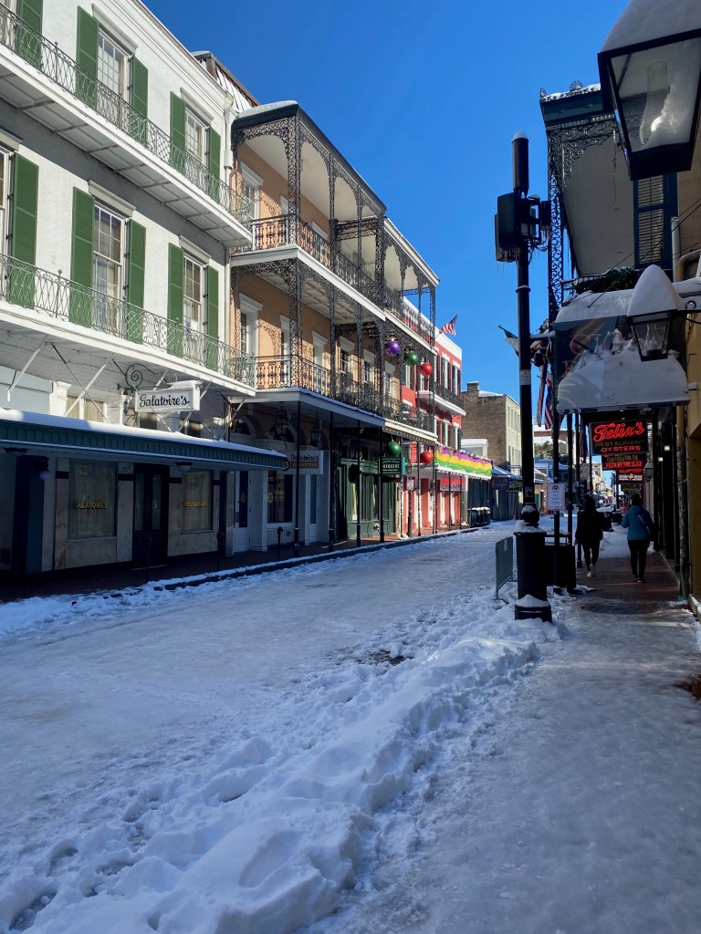Bourbon Street in New Orleans is covered in ice, with few people attempting to walk on it.