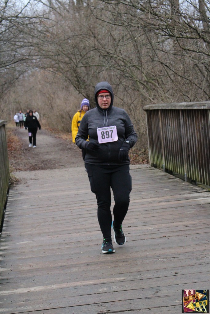 A woman wearing athletic clothes runs across a wooden bridge.
