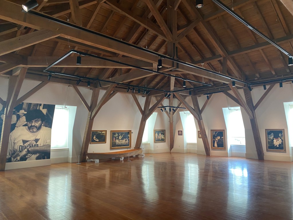 An art gallery underneath an arched wooden roof.