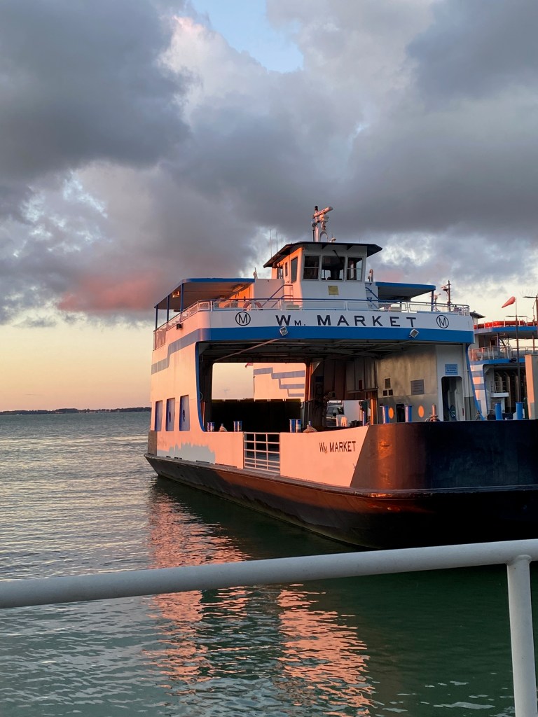 A car ferry sits at the dock with sunlight reflecting off it.