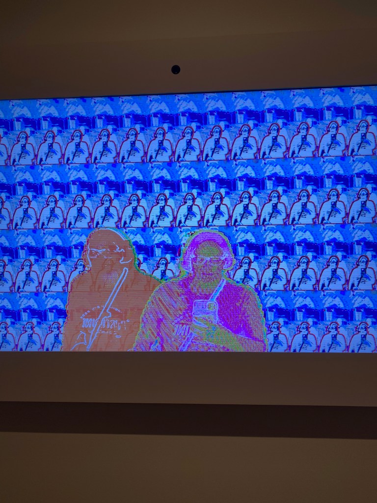 A screen shows pixelated video of a woman standing in front of it, repeated numerous times.