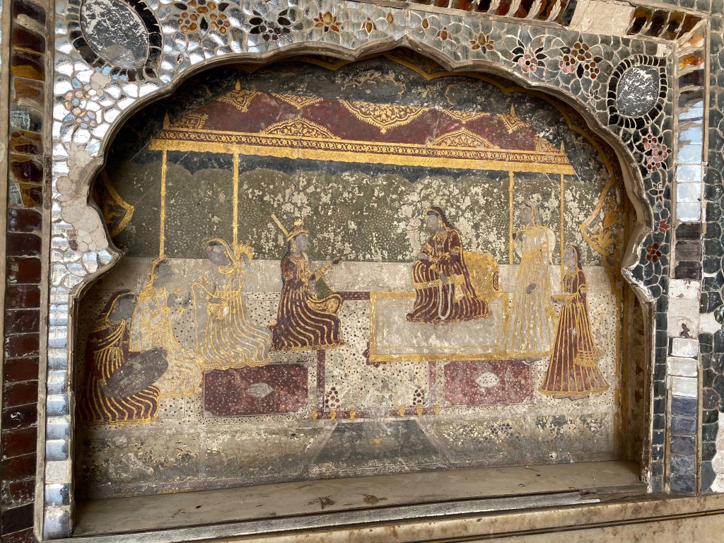 A faded fresco on the wall, surrounded by shards of mirrored glass.