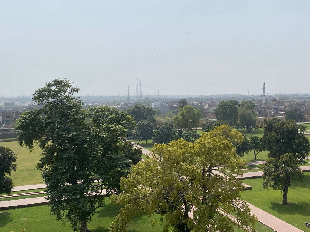 A low-lying city is visible in the background, with trees and a park in the foreground.